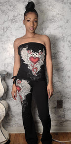 Woman wearing a black strapless top with floral embroidery against a textured wall.