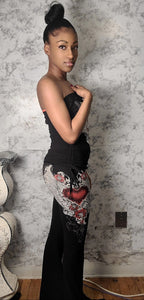 Woman wearing a black dress with floral designs against a textured wall.