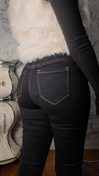 Person wearing black jeans and a white fur vest with a blurred background