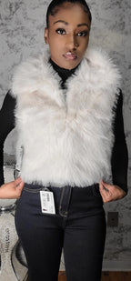 Person wearing a white fur vest with a gray background